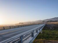 a long bridge spans over the pacific ocean near a sandy beach with a small town in the background