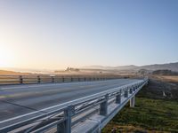 a long bridge spans over the pacific ocean near a sandy beach with a small town in the background