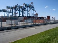 a very long empty road by the shipping yard with a dock to the side of it