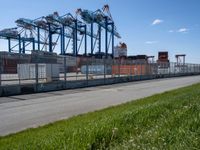 a very long empty road by the shipping yard with a dock to the side of it