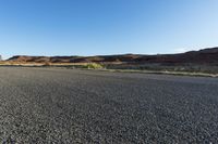 a long empty road with no cars on it, in the desert, in front of mountains and sky