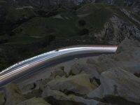 there is a long exposure photo of a curve on a mountain road through some rocks