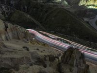 there is a long exposure photo of a curve on a mountain road through some rocks