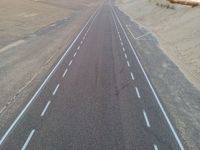 a large long highway that is next to the ocean in the sand near water and a sandy beach