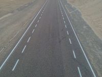 a large long highway that is next to the ocean in the sand near water and a sandy beach