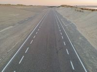 a large long highway that is next to the ocean in the sand near water and a sandy beach