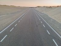 a large long highway that is next to the ocean in the sand near water and a sandy beach