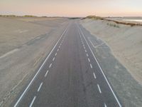 a large long highway that is next to the ocean in the sand near water and a sandy beach