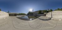 a view of the inside of a skate park showing an outside fountain area with benches on the bottom