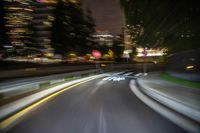 motion blurry shot of a long road at night with a traffic signal and city skyline in the background