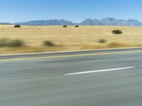 a picture of a long road with mountains in the background on a clear day - long road