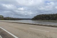 a view of a long road in front of the water on a cloudy day with a few clouds