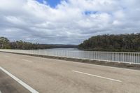 a view of a long road in front of the water on a cloudy day with a few clouds