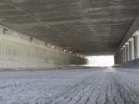 a skate boarder rides up to the top of a ramp in a long tunnel