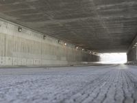 a skate boarder rides up to the top of a ramp in a long tunnel