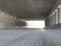 a skate boarder rides up to the top of a ramp in a long tunnel