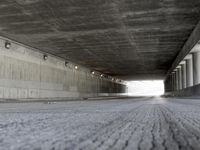 a skate boarder rides up to the top of a ramp in a long tunnel