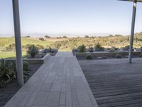 a long walkway leading to a patio with a lawn on the other side and a large open door