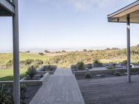 a long walkway leading to a patio with a lawn on the other side and a large open door