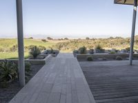 a long walkway leading to a patio with a lawn on the other side and a large open door