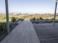 a long walkway leading to a patio with a lawn on the other side and a large open door