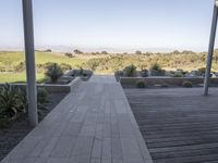 a long walkway leading to a patio with a lawn on the other side and a large open door