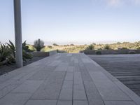 a long walkway leading to a patio with a lawn on the other side and a large open door