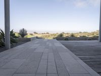 a long walkway leading to a patio with a lawn on the other side and a large open door