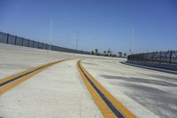 a long yellow line on a deserted road next to traffic light poles and fenced off area