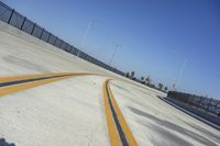 a long yellow line on a deserted road next to traffic light poles and fenced off area