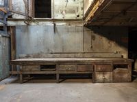 a rusty table sits in front of a wooden door in an abandoned building with large, peeling metal and exposed wooden walls