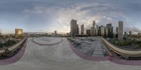 a 360 camera lens image of a skate park in a city with a sunset over the water