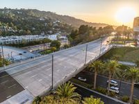 an aerial view of a highway over some trees and parked cars under the street light