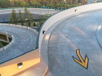 a curved roadway with traffic cones and an arrow on the road in front of it