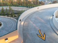 a curved roadway with traffic cones and an arrow on the road in front of it