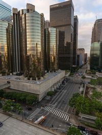 a group of tall buildings stand next to an intersection in a downtown area with cars and people in the city