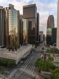 a group of tall buildings stand next to an intersection in a downtown area with cars and people in the city