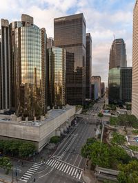 a group of tall buildings stand next to an intersection in a downtown area with cars and people in the city