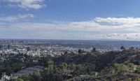 a large view of the city skyline from a cliff near the hills to town in the distance