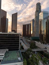 some skyscrapers are sitting along the highway at sunset with some clouds in the sky