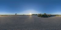 a 360 - camera image of a desert scene at sunset with trees and shrubs, with a person on a skateboard passing