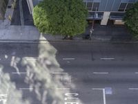 a bird's eye view of the sidewalk on a city street with cars driving down it