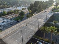 a freeway filled with lots of cars and lots of palm trees in the distance behind an overhead