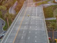 an aerial view of two yellow vans driving along a freeway with trees and palm trees