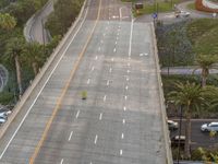 an aerial view of two yellow vans driving along a freeway with trees and palm trees