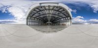 this is a wide angle shot of a airplane hangar on the ground while the plane flies in the air