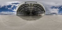 a long walkway of cement leading to an airplane hangar with an airplane boarding door open