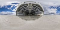 a long walkway of cement leading to an airplane hangar with an airplane boarding door open