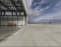 an airplane is parked inside an open airport hangar next to a concrete ramp in between two windows