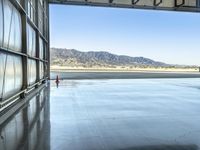 a man is walking to an airplane parked in a hangar on the tarmac that holds a plane